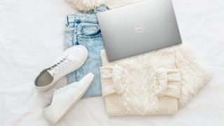 Dell XPS 13, along with a sweater, jeans and some cute shoes on a white background.