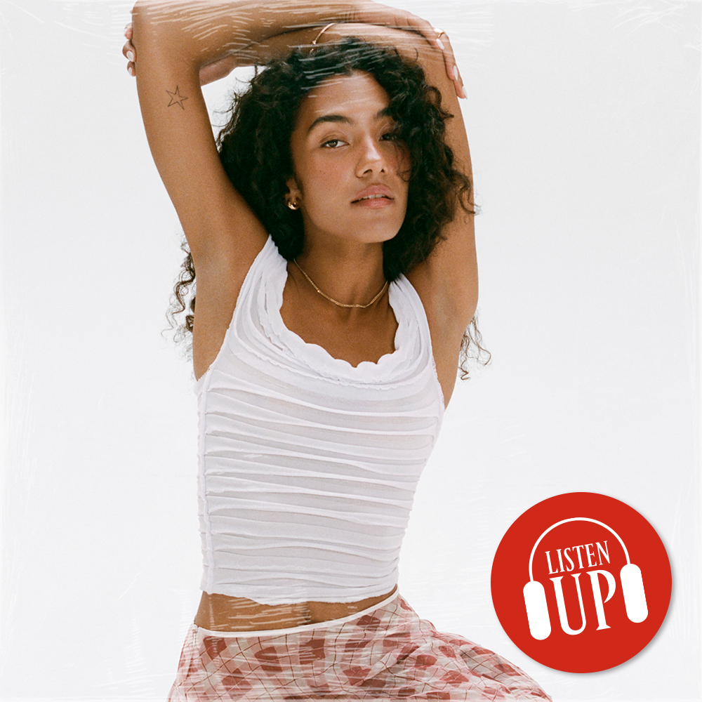 an image of singer olivia dean in a white shirt and red check skirt lifting her hands over her heads the logo for marie claire&#039;s listen up franchise on top