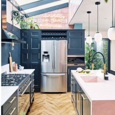 kitchen with dark blue cabinets, silver fridge freezer, pink island, black hob and skylights