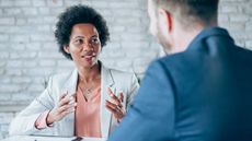 A woman gestures as she talks with a hiring manager during a job interview.