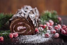 Close up of classic Christmas dessert chocolate Yule log decorated with cranberries