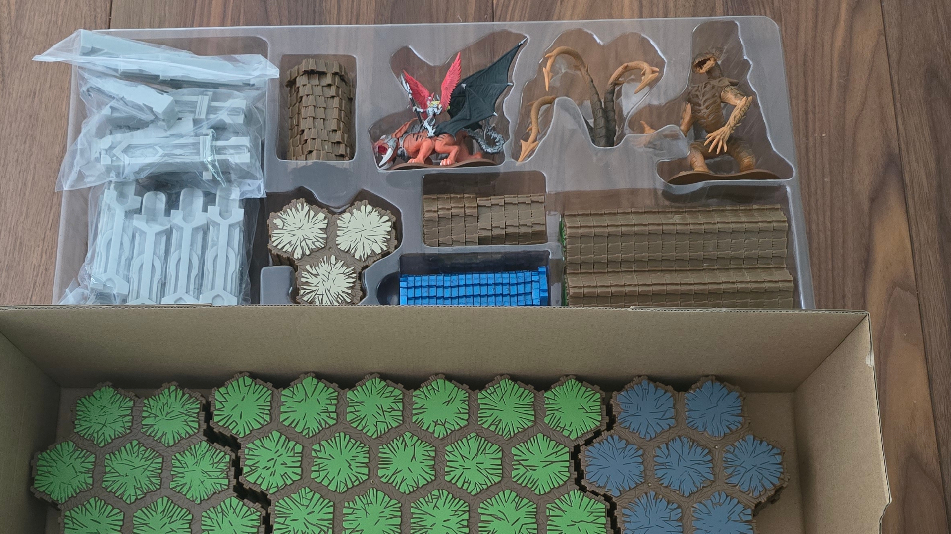 Packaged Heroscape models and terrain laid out on a wooden surface