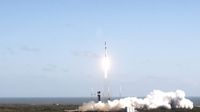 a black and white rocket launches into a blue sky