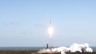 a black and white rocket launches into a blue sky