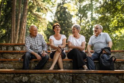Two senior couples sitting in park on bench, taking a break from walking