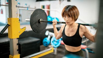 Woman exercising by doing squats in the gym