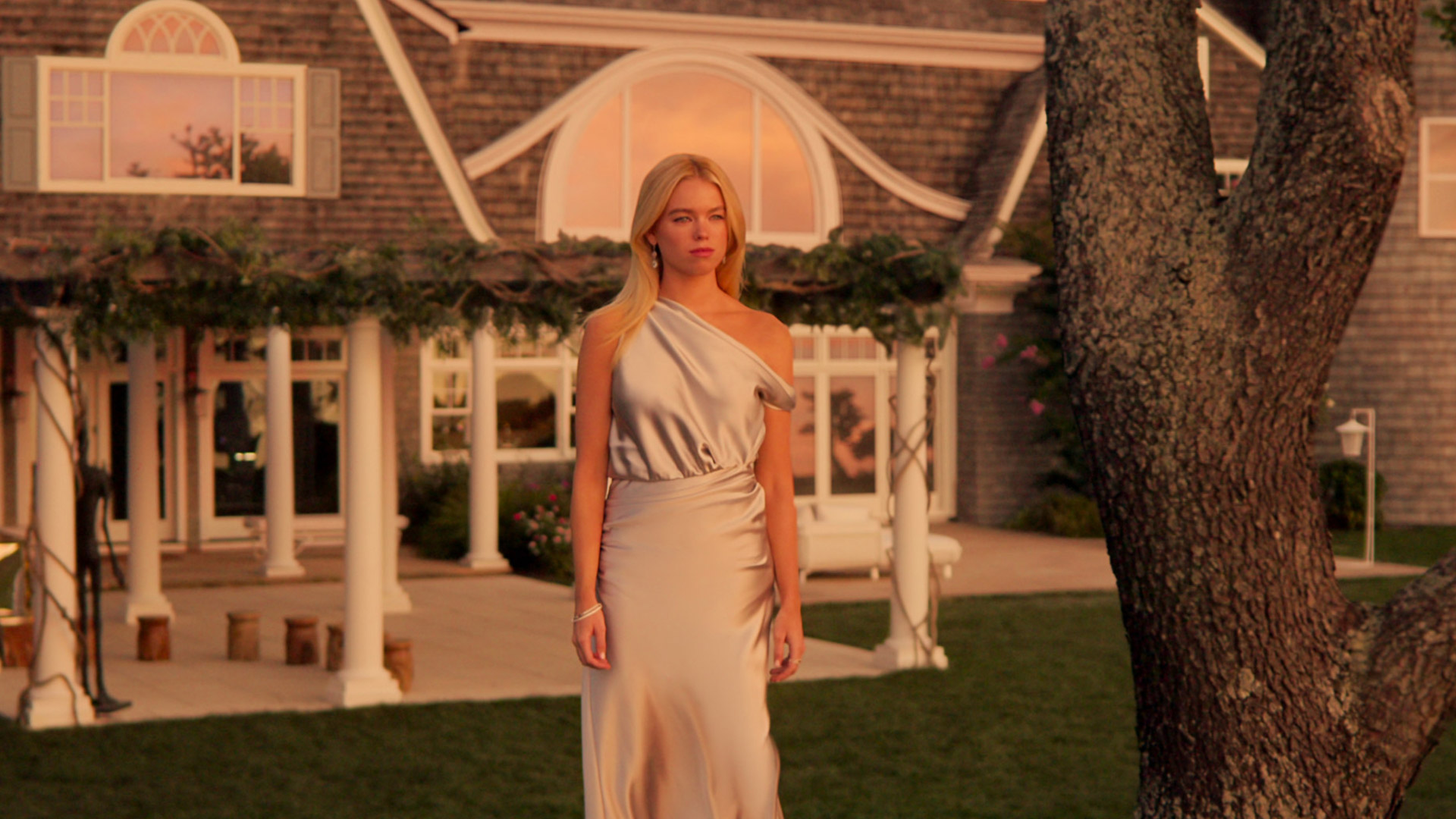 Milly Alcock stands in front of a house in Sirens