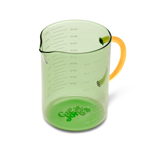 A green tinted glass measuring cup with yellow handle