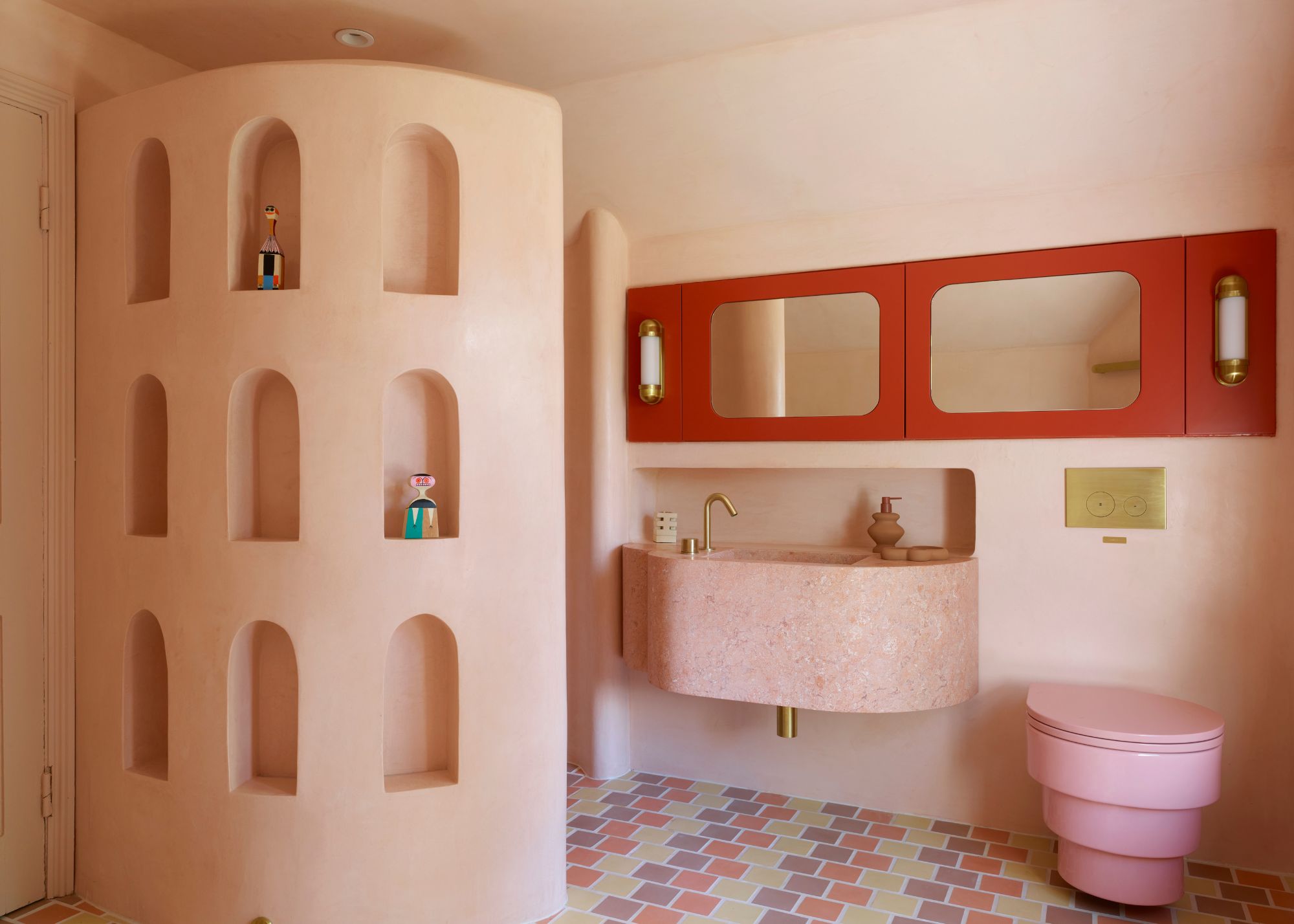 A bathroom with pink walls, red cabinets and multicolored floor tiles