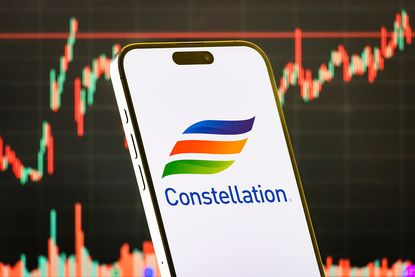 Constellation Energy logo on smartphone with stock market chart background