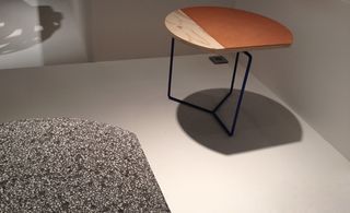 White walls, white viewing platform, low wooden top table with black metal frame, bland grey speckled design table top