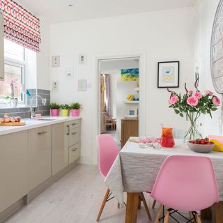 kitchen with white wall wooden table and pink chair