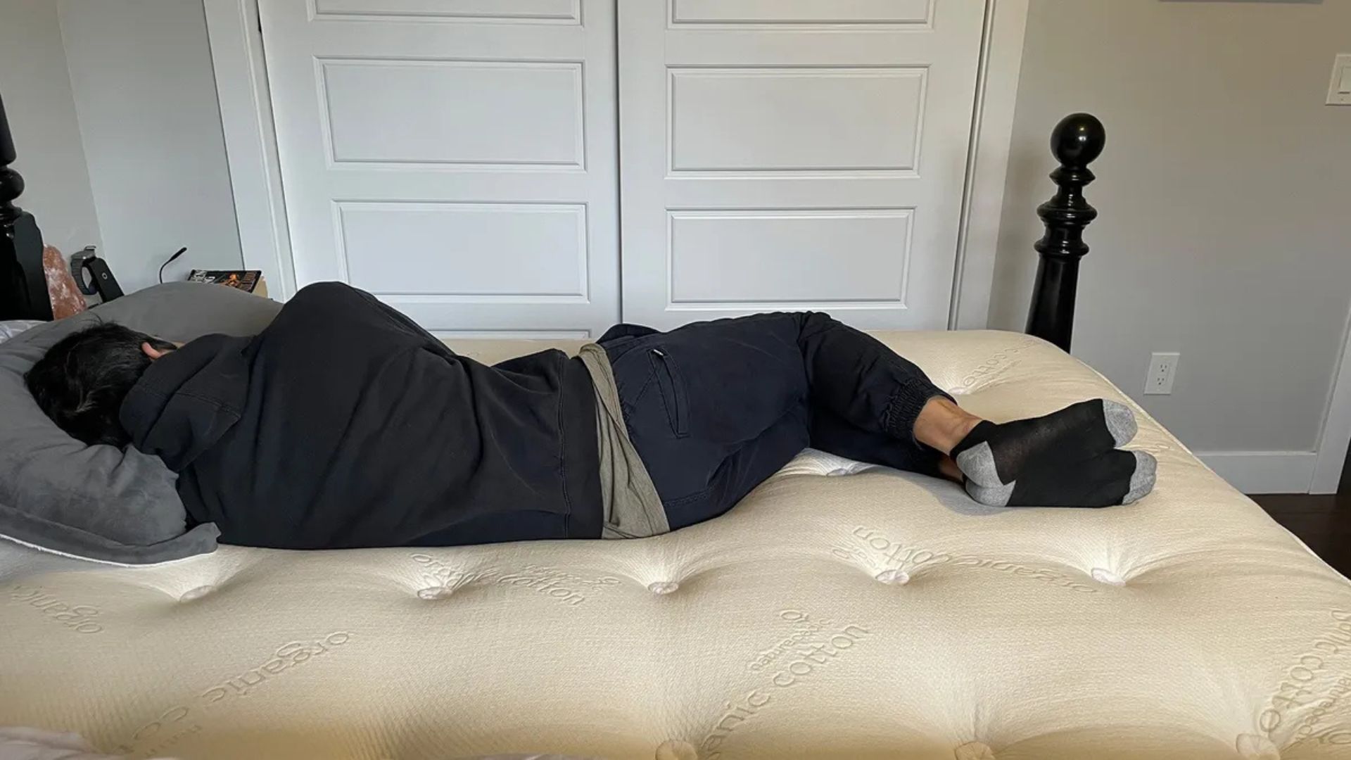 A Tom's Guide tester lying on his side on the Naturepedic Concerto Pillowtop mattress