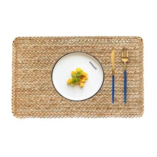 A rectangular jute placemat with a white plate and a blue knife and fork