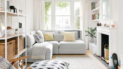 Grey corner sofa in white living room with floor to ceiling windows and shelves