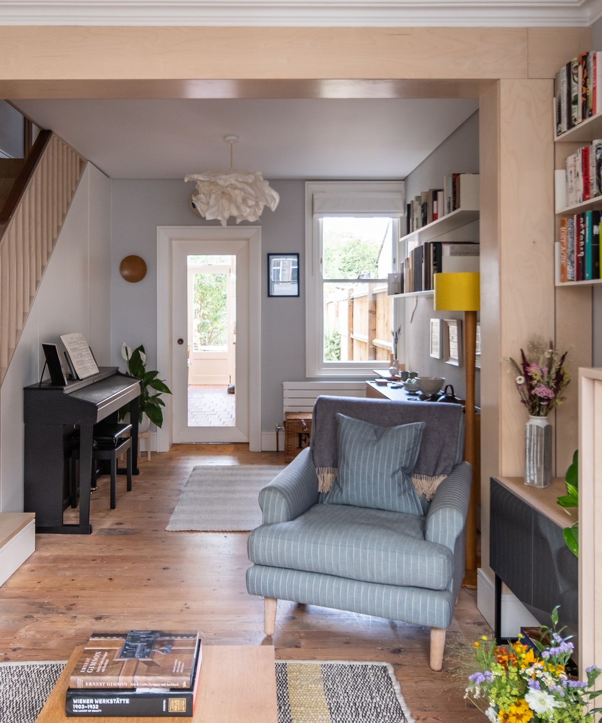 A large reception room in a Victorian house with wooden floorboards and a plywood divider