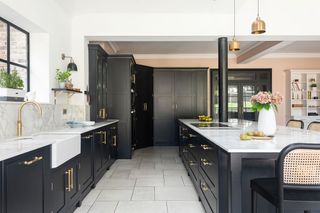 gray kitchen units and white worktops and flooring with steel framed windows