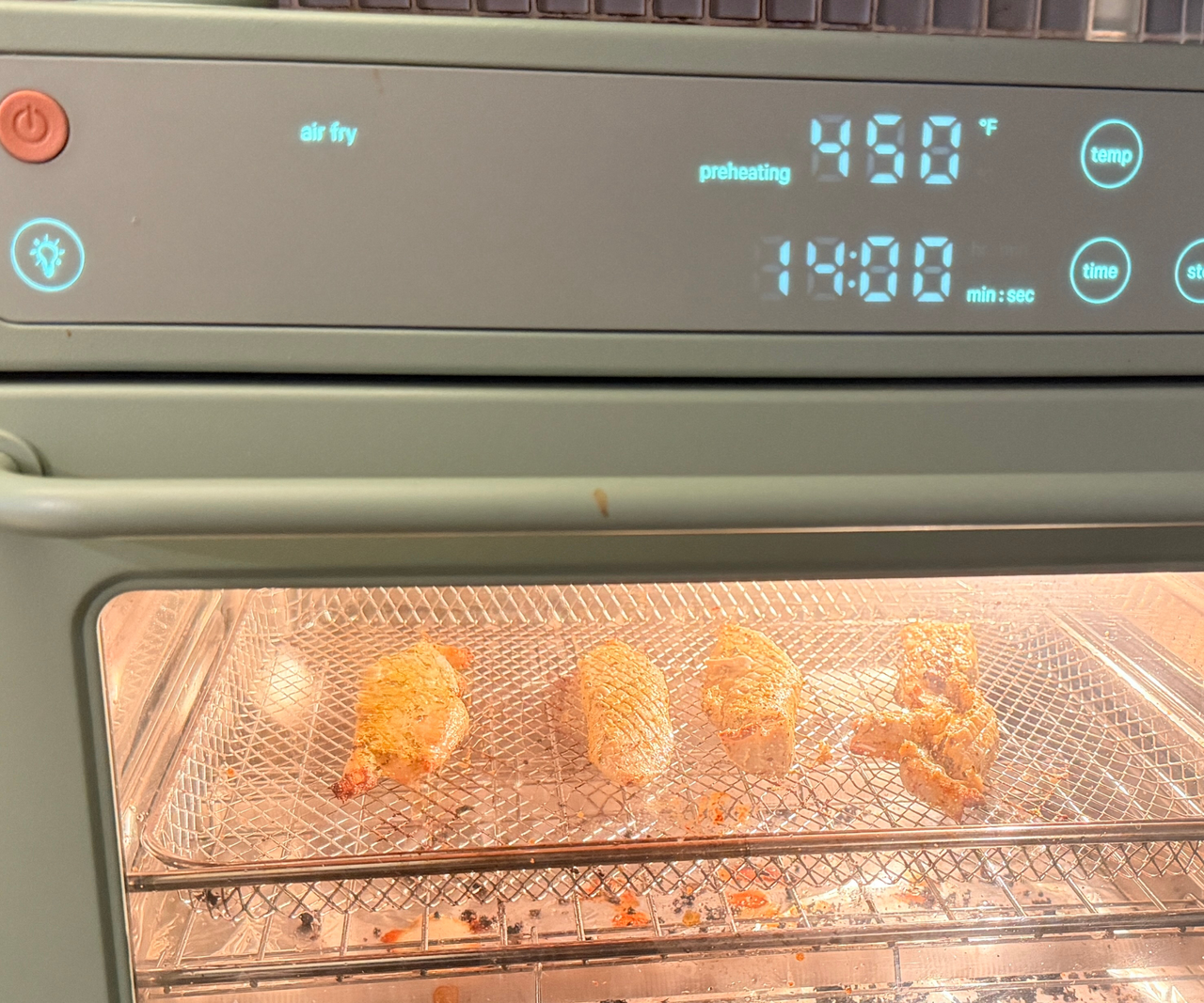 A close up of the blue digital display on the front of a light green Wonder Oven air fryer.