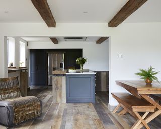 A kitchen with dark grey-blue island in open plan space with reclaimed bark oak floors