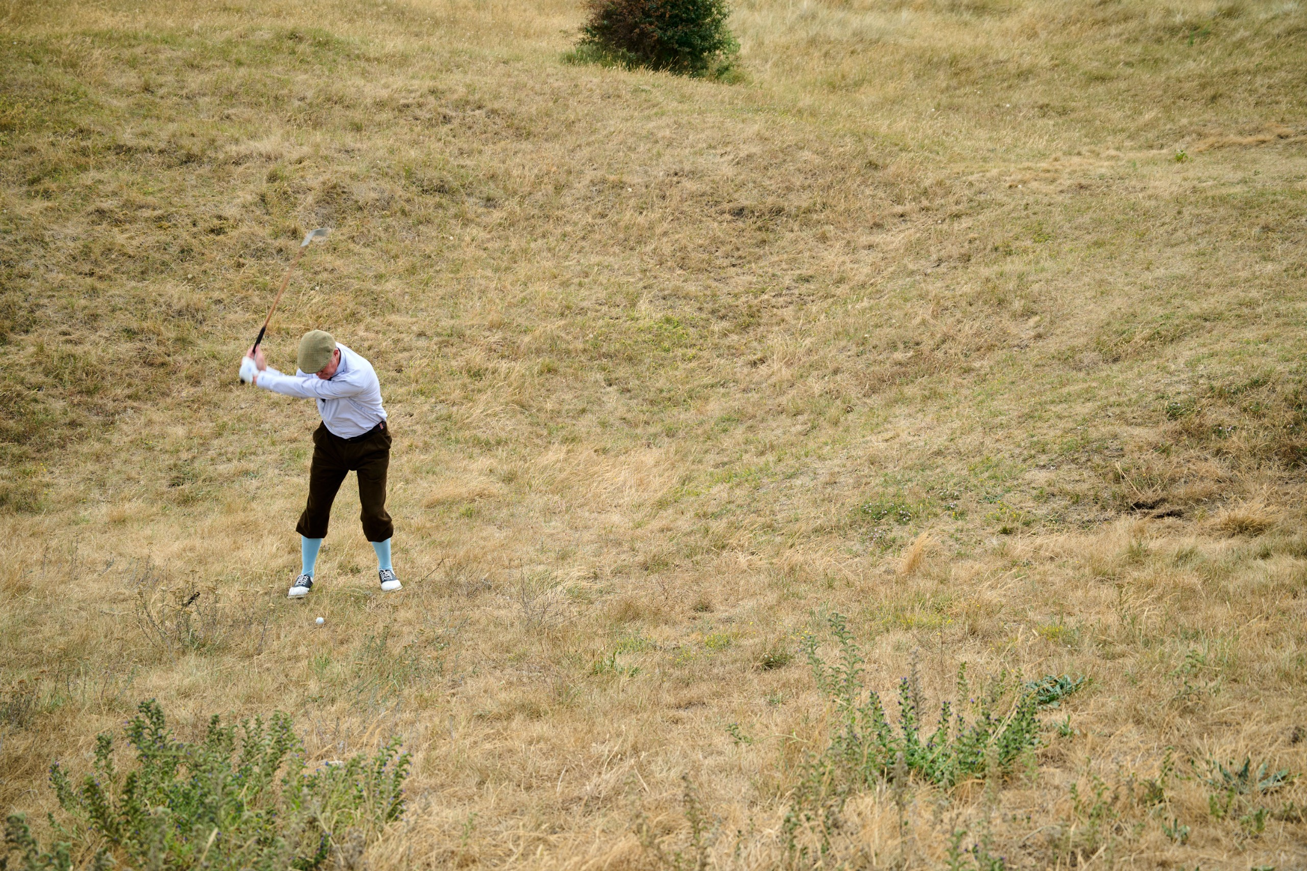 Fergus Bisset playing a golf shot on an upslope
