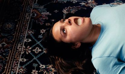 A woman lying on a patterned carpet with her mouth open.