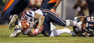 Chris Harris (25) of the Denver Broncos tackles Aaron Hernandez (81) of the New England Patriots on Dec. 18, 2011. After his death, Hernandez was found to have a degenerative brain disease that has been linked to head impacts.