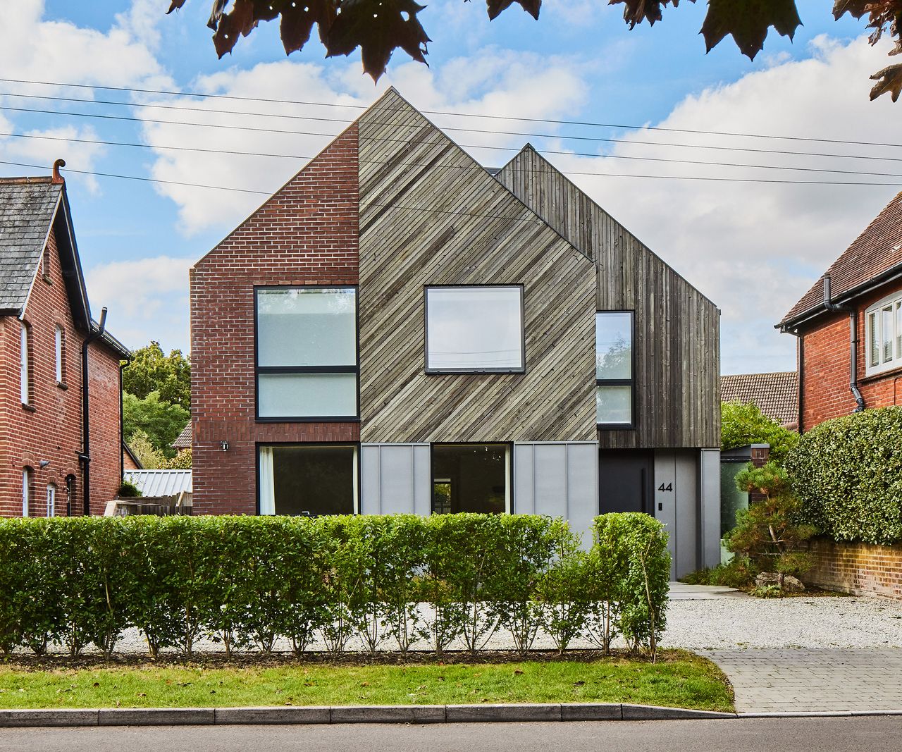 The front view of a new self build home clad in timber and brick. The roof is pitched and the build has clean lines and smooth glazing
