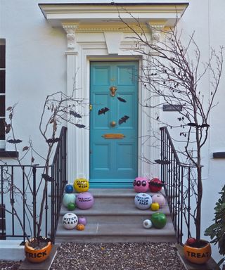 Blue front door with adhesive bat decor, painted pumpkin with slogans and pumpkin tree decor