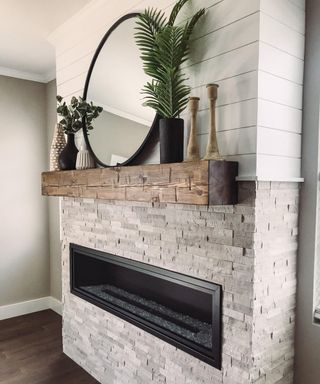 Rustic beam mantel above contemporary fitted fireplace and textured wall.