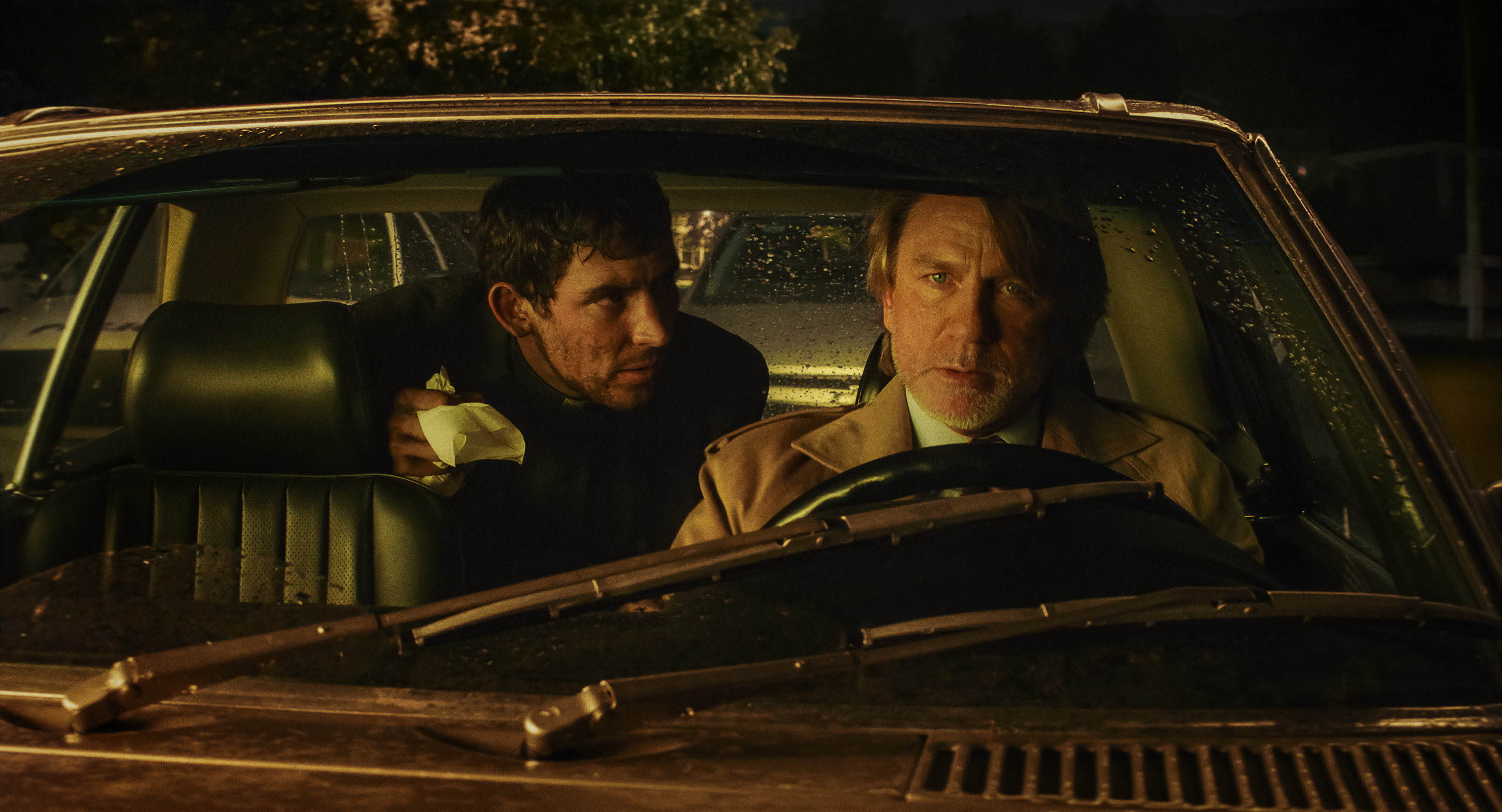 Father Jud in the back seat of Benoit Blanc&#039;s car talking to Benoit