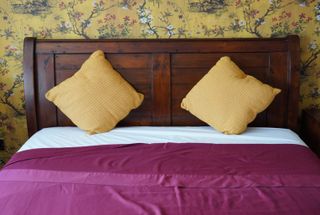 a red flat sheet with yellow pillows on top