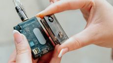 A model's hand holding the iFi Go Blu Air portable Bluetooth DAC