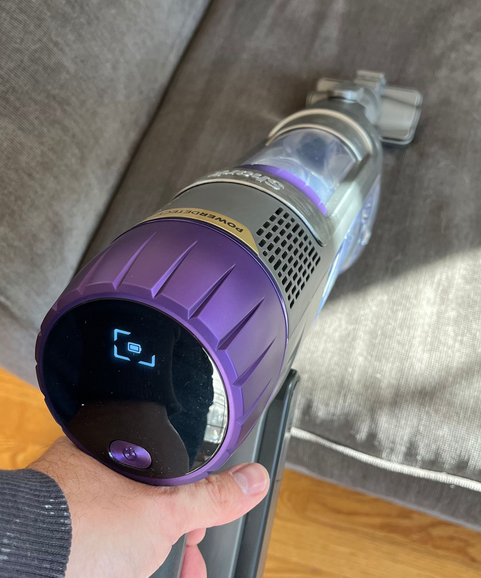 Shark Cordless PowerDetect in handheld mode, vacuuming a gray sofa