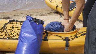 Person packing dry bags into a kayak