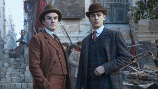 Donal Finn as James Moriarty and Hero Fiennes Tiffin as Sherlock Holmes standing in the wake of disaster for Prime Video's Young Sherlock