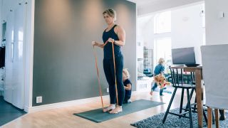 Woman performs biceps curl with a resistance band in her living room