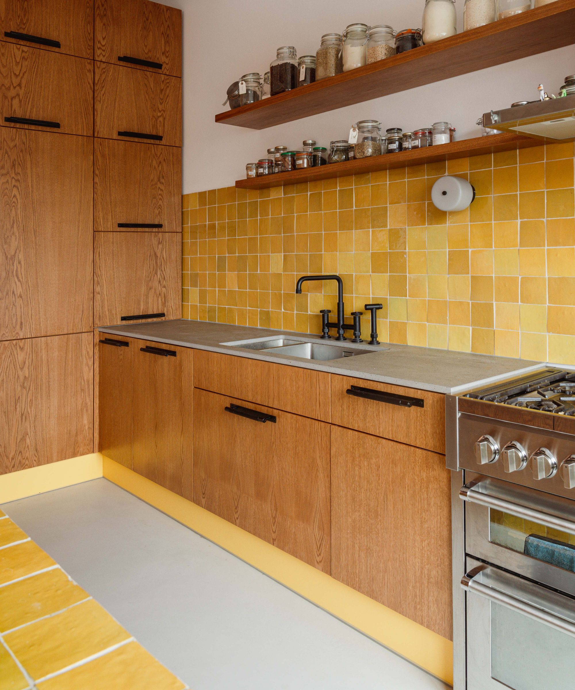 Wood kitchen with yellow tiled splashback and skirting board plinth