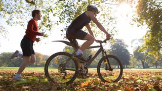 Cyclist and runner training together in park