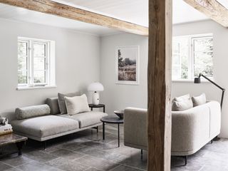 Living room with grey sofas and visible wooden beams and columns from the original farm architecture