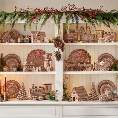 Pottery Barn's Christmas tableware with gingerbread designs displayed in a cabinet with a garland on top