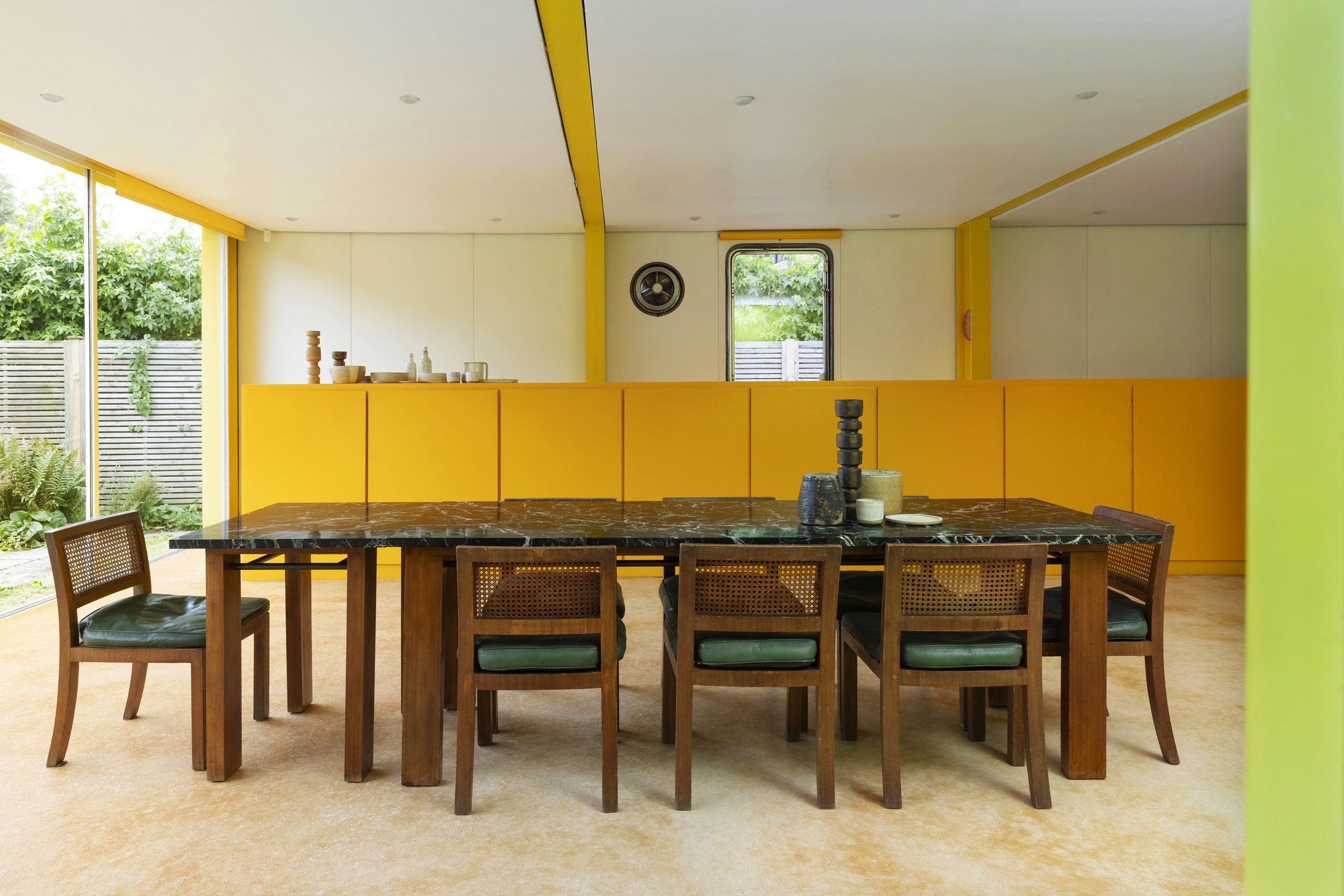 the interior of 22 parkside, a dining table with orange cabinets and a green and wood marble table
