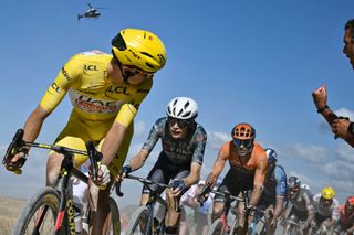 UAE Team Emirates team's Slovenian rider Tadej Pogacar wearing the overall leader's yellow jersey looks back as he cycles ahead of Team Visma - Lease a Bike team's Danish rider Jonas Vingegaard (2nd L) over a "Chemin Blanc" (white road) gravel sector during the 9th stage of the 111th edition of the Tour de France cycling race, 199km stage departing and finishing in Troyes, on July 7, 2024. (Photo by Marco BERTORELLO / AFP)