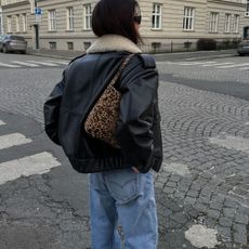 Influencer @annabelrosendahl wears blue jeans with a leather sheepskin jacket and a leopard print bag.