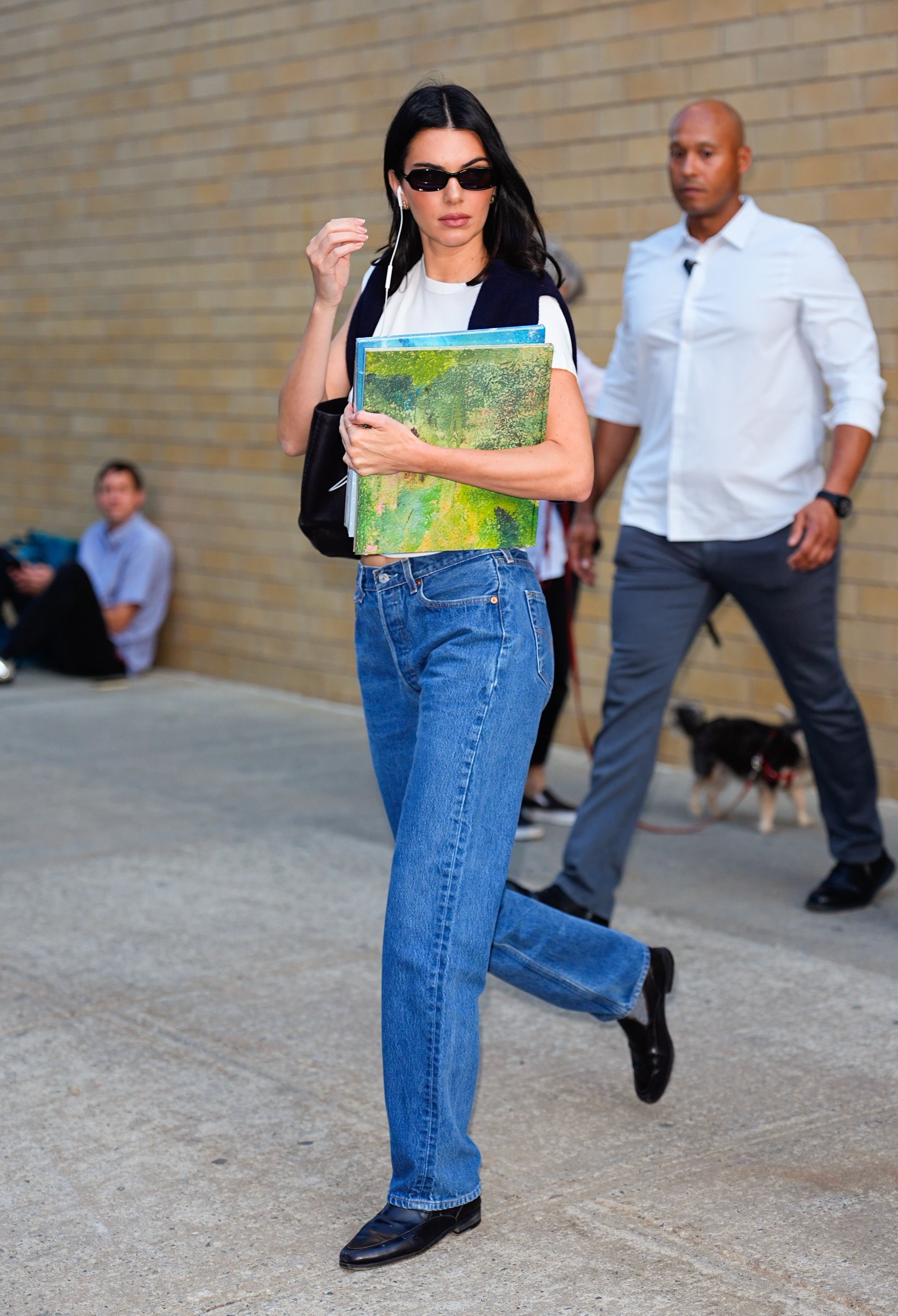 Kendall Jenner walks down the street wearing stovepipe jeans with black leather loafers and a white tee.