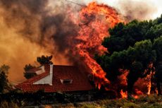 Flames reach a home near Athens, Greece, on Monday.