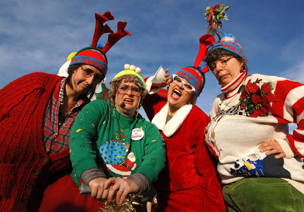 Four women wearing ugly Christmas sweaters.