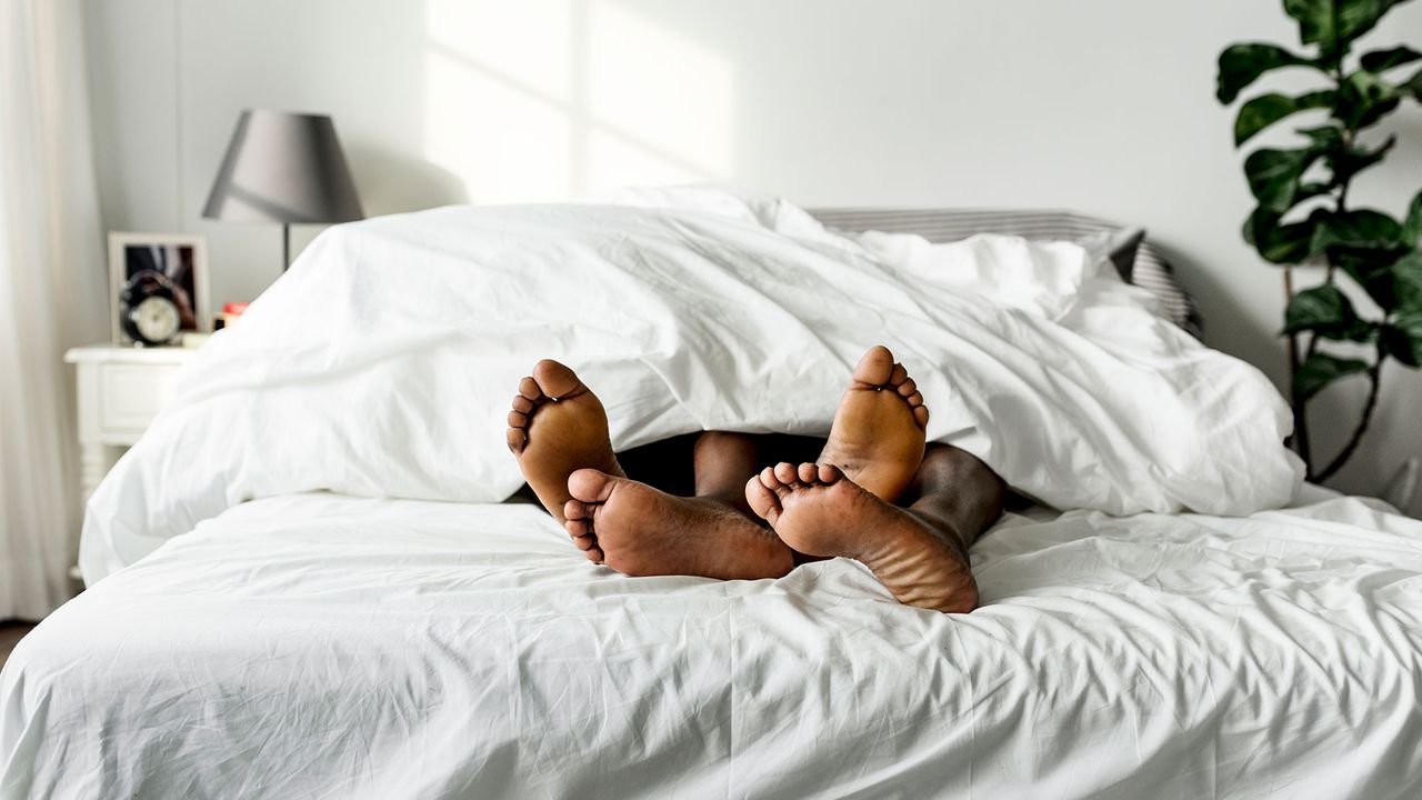 Two pairs of feet poking out from under the covers