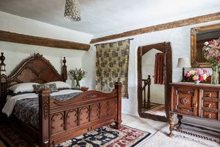 double bedroom with dark wood furniture beams and limewashed walls
