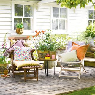 Outdoor deck area with two chairs and colourful patterned cushions