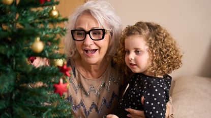 Grandmother and granddaughter decorating the christmas tree together, enjoying precious family moments during the festive season